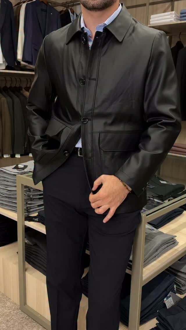 Man wearing a black leather jacket and navy trousers in a clothing store