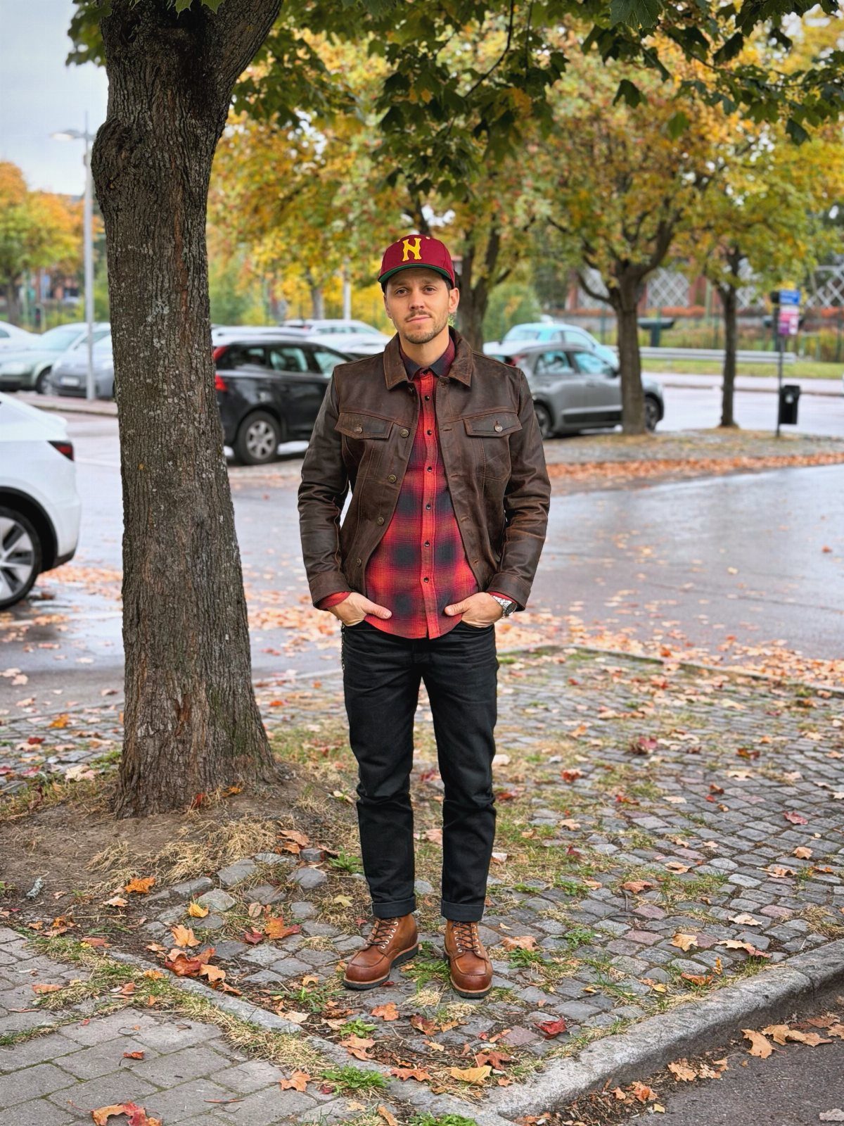 Man wearing a brown leather jacket over a red flannel shirt and black jeans