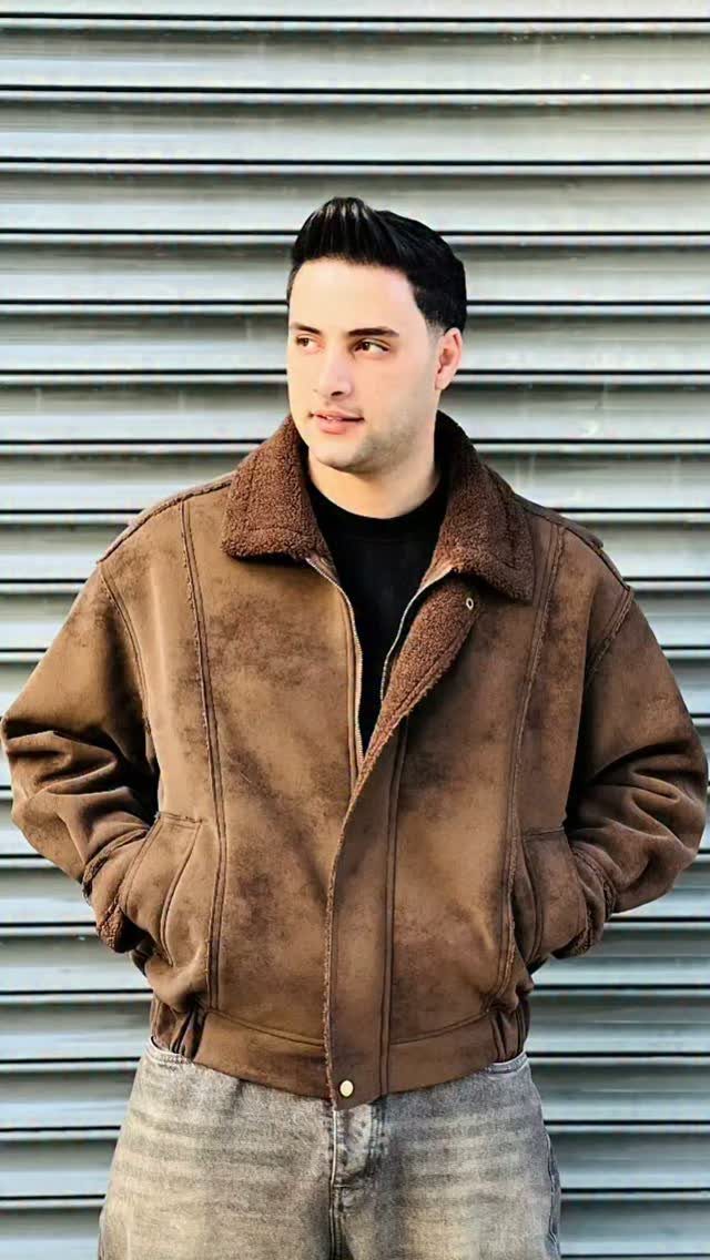Man in light brown suede jacket with faux-fur collar and grey jeans.