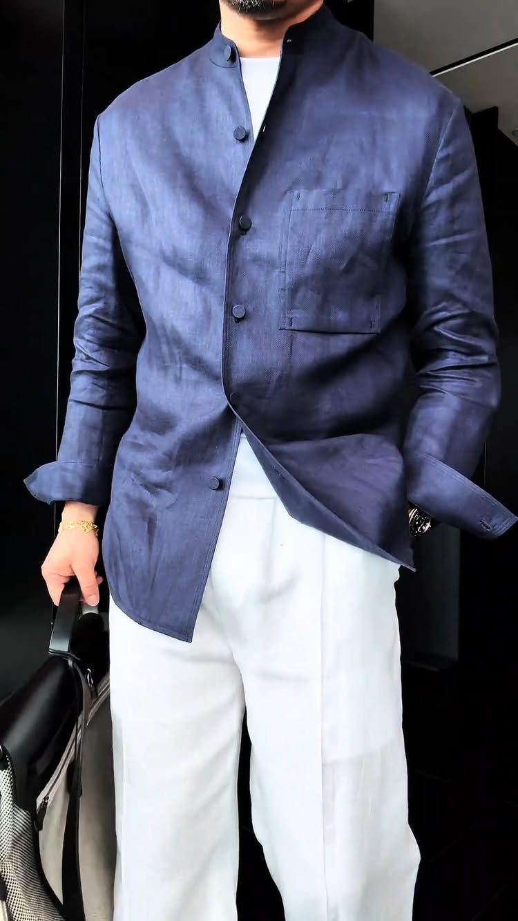 Man wearing a navy blue linen blazer and white linen trousers in a minimalist setting