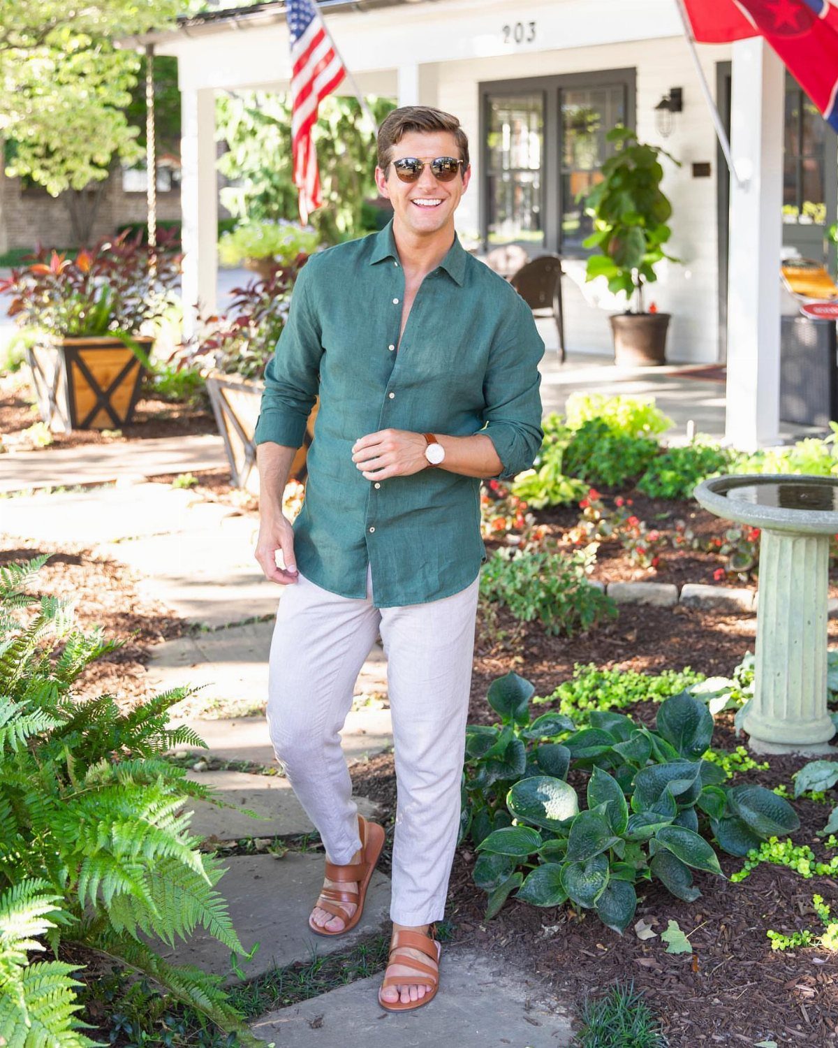 Man in green linen shirt and beige linen pants standing in a garden
