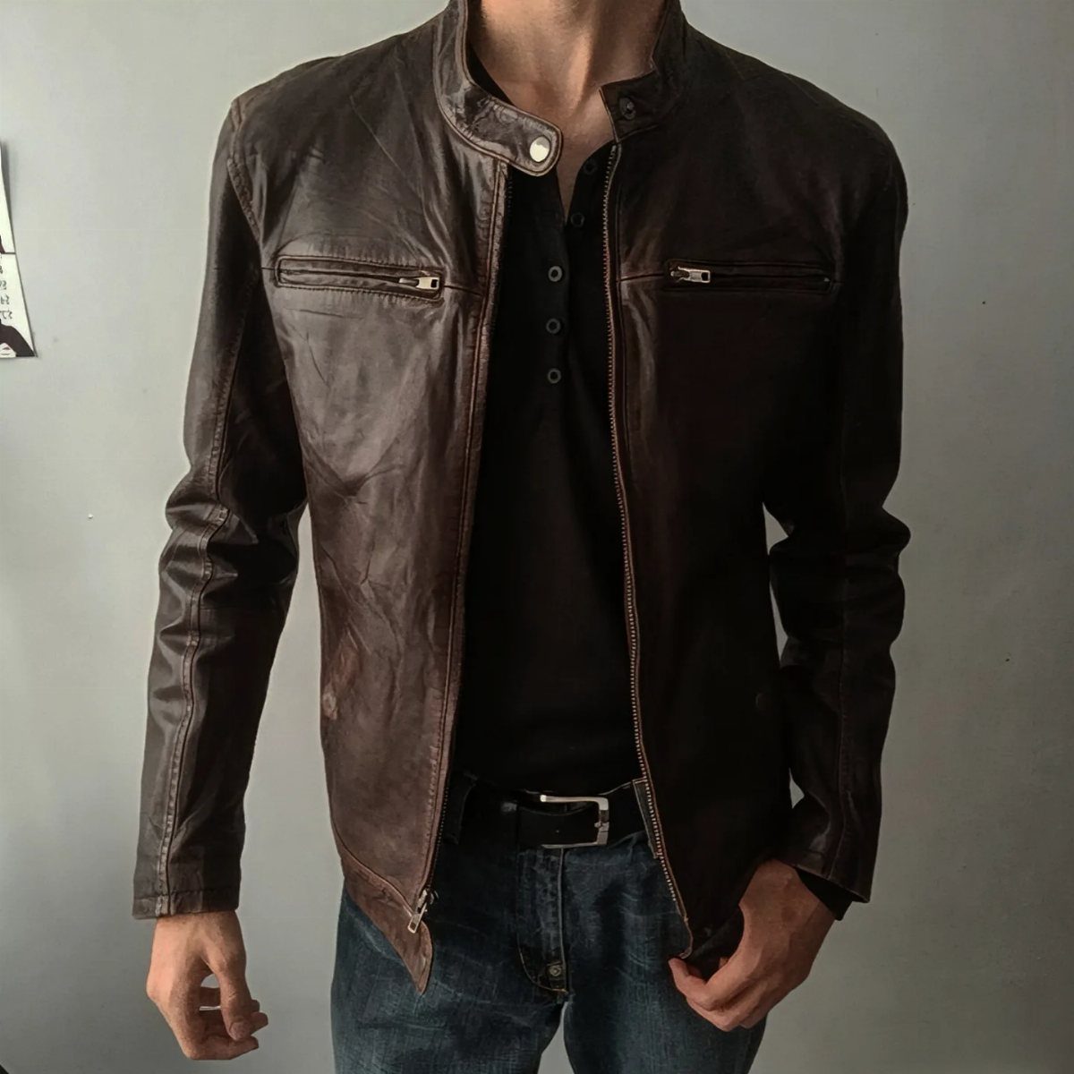 Man wearing a brown leather biker jacket over a black Henley shirt and jeans.