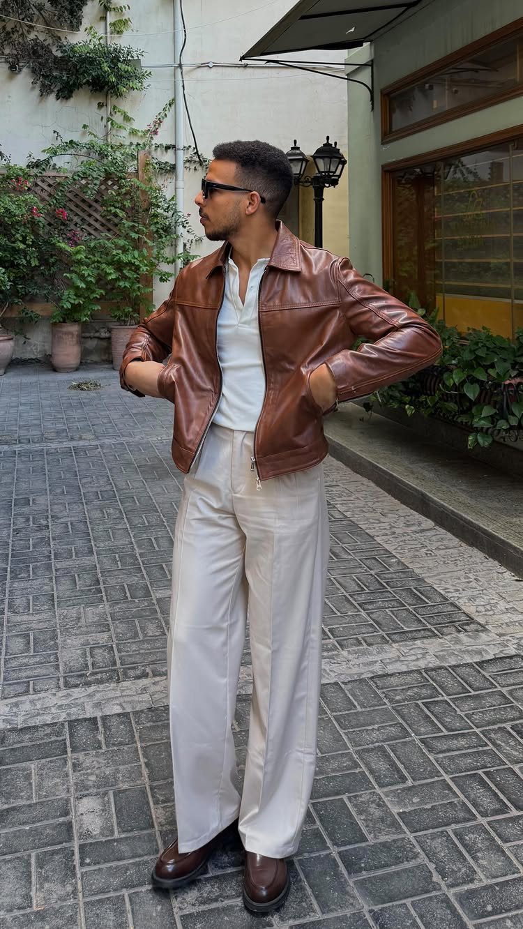 Man wearing a brown leather jacket, white shirt, and cream wide-leg trousers.