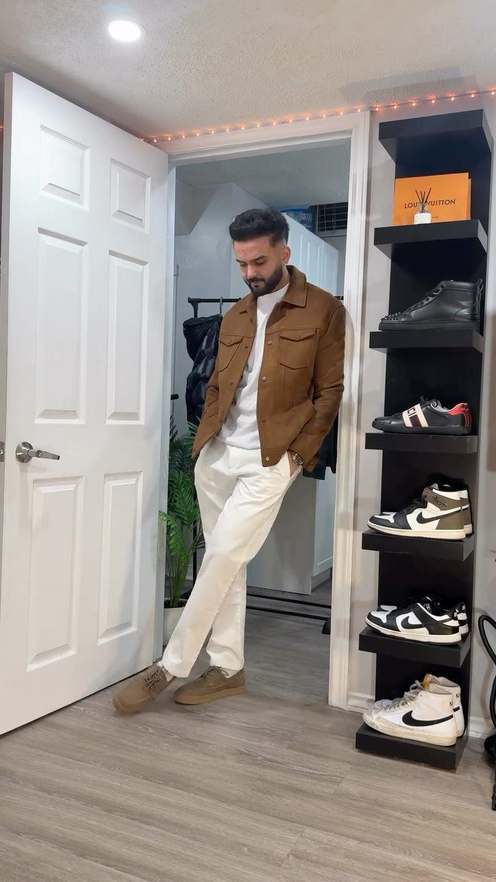 Man wearing a brown leather jacket with white pants and tan suede boots.