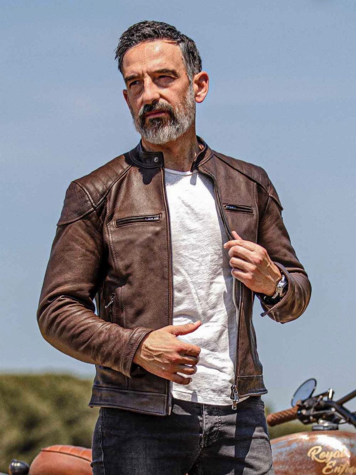 Man with grey beard wearing a brown leather jacket and white t-shirt.