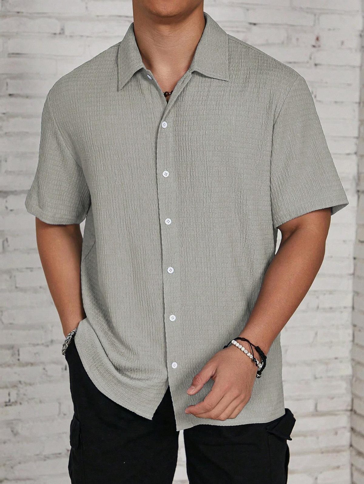Man wearing a light grey short sleeve button-down shirt and black cargo pants.