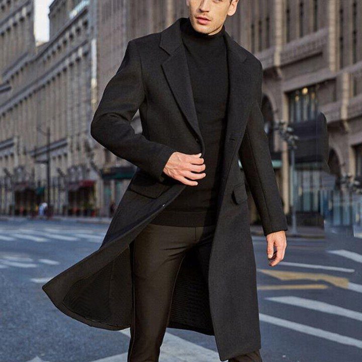 Man in a long black wool overcoat and turtleneck walking on city street