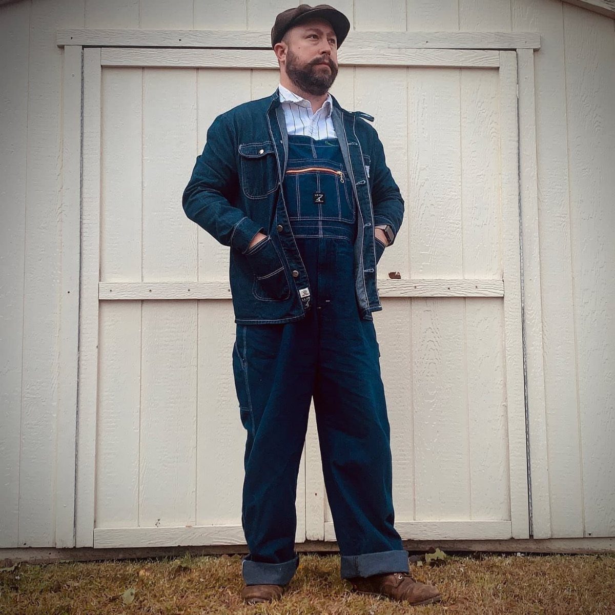 Man wearing denim overalls, a white button-down shirt, and a denim jacket.