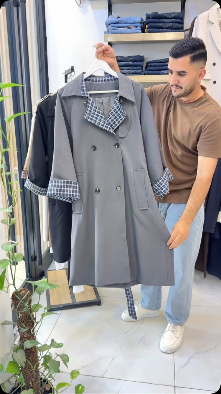 Grey trench coat with blue plaid collar and cuffs held by a man.