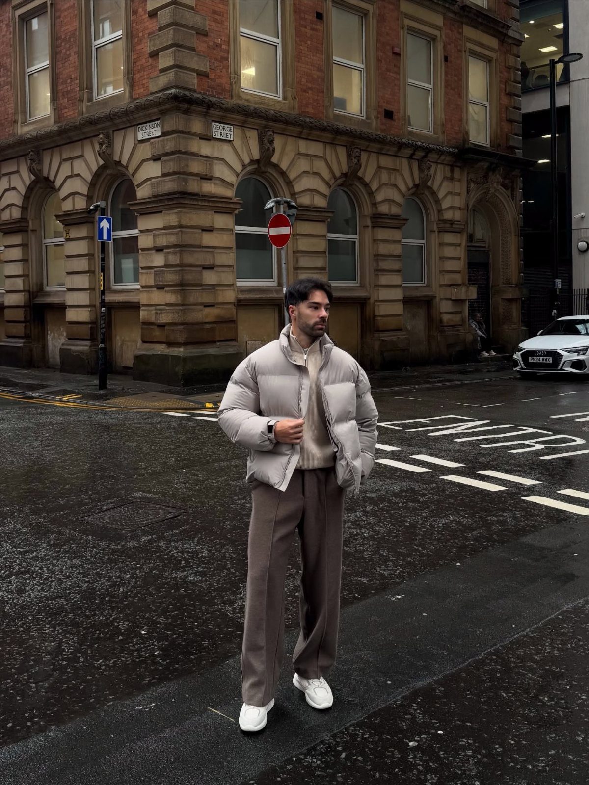 Man wearing a beige puffer jacket and matching trousers on a city street