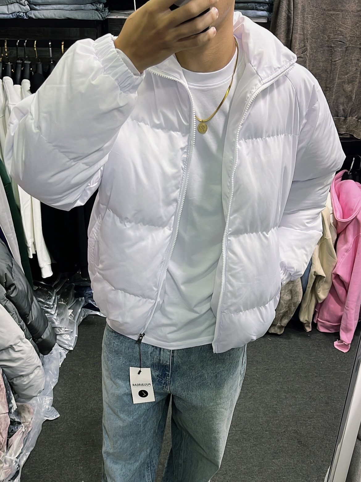 Person wearing a white puffer jacket, white t-shirt, and light blue jeans.