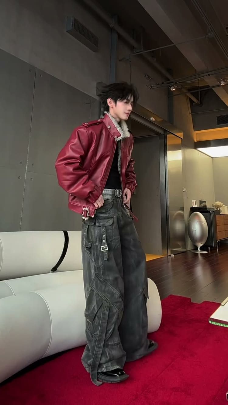 Person wearing a red leather jacket and oversized grey cargo pants in a room.
