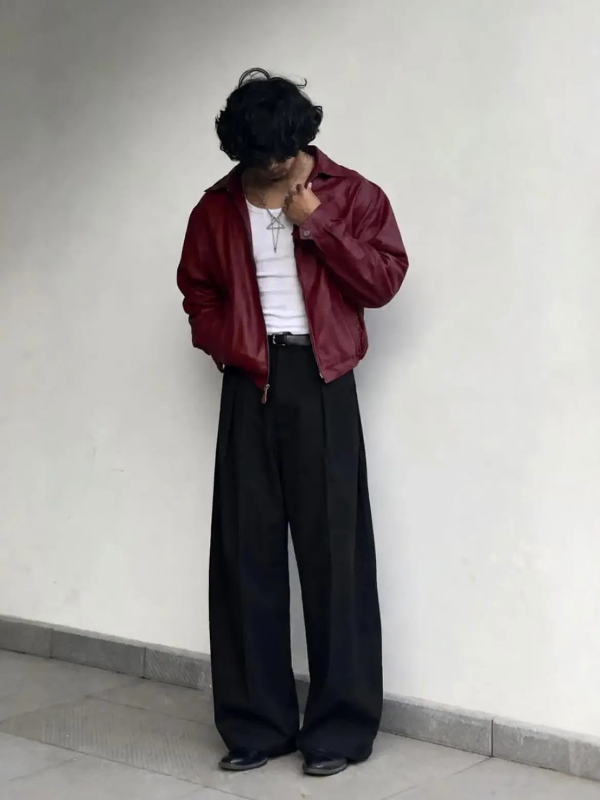 Person wearing a red leather jacket, white t-shirt, and wide black trousers.