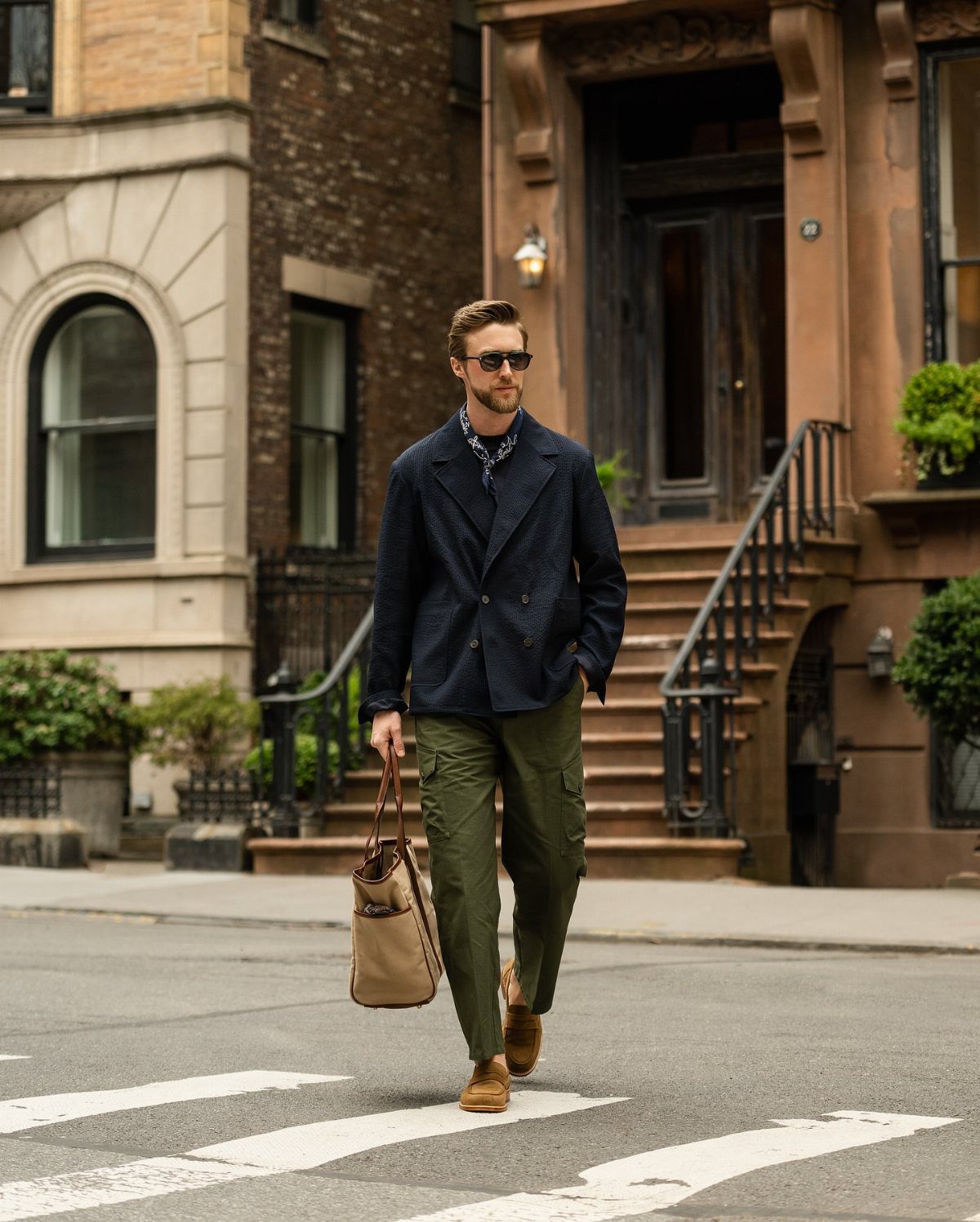 Man in navy blazer and olive cargo pants walking on city street
