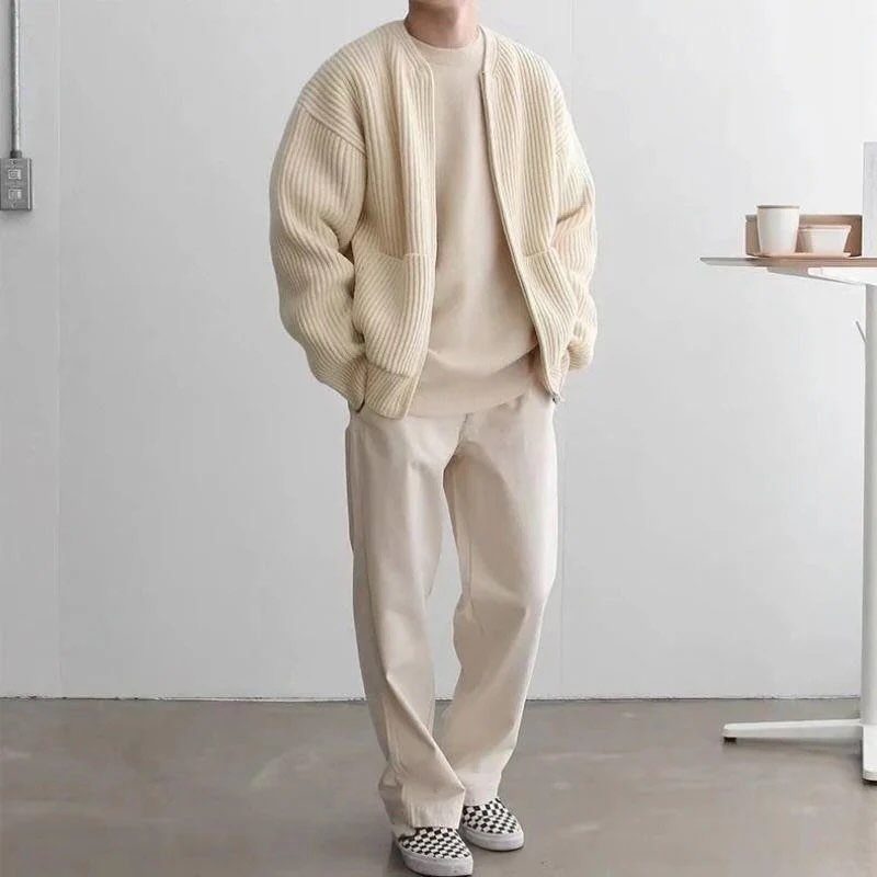 Man in cream ribbed cardigan, matching t-shirt, and beige trousers with checkered shoes.