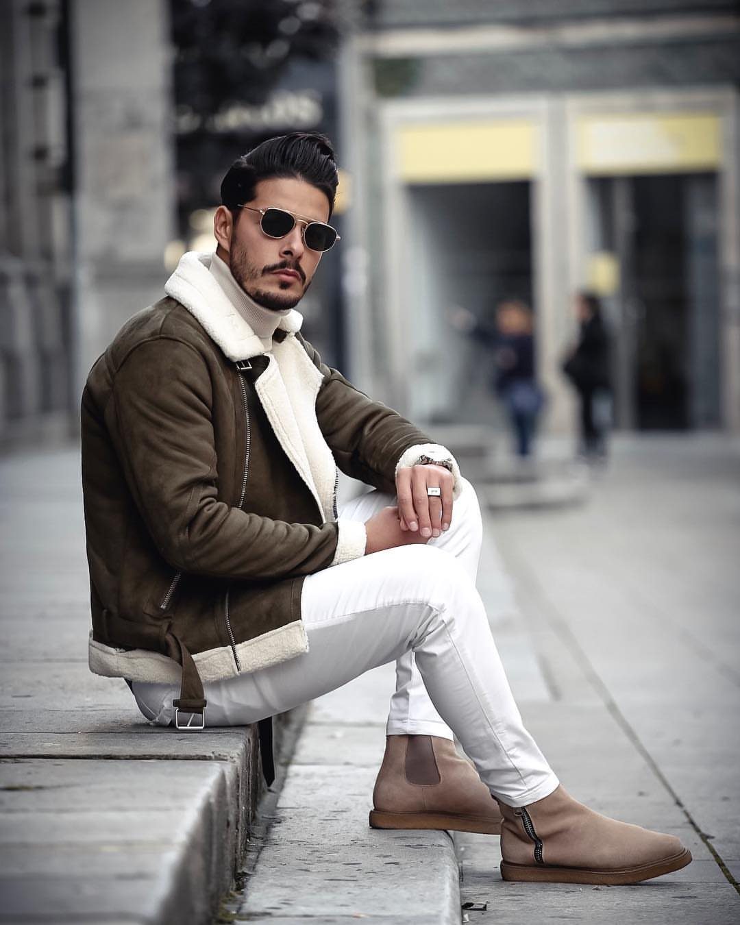 Man in brown shearling jacket and white pants wearing tan suede Chelsea boots.