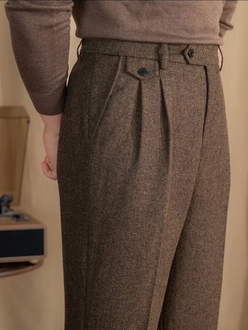 Brown herringbone wool trousers with pleats paired with a matching brown sweater.