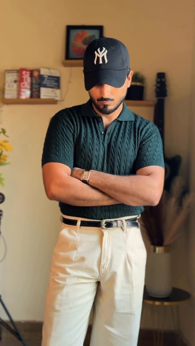 Man wearing a dark green textured polo shirt, cream trousers, and black cap.