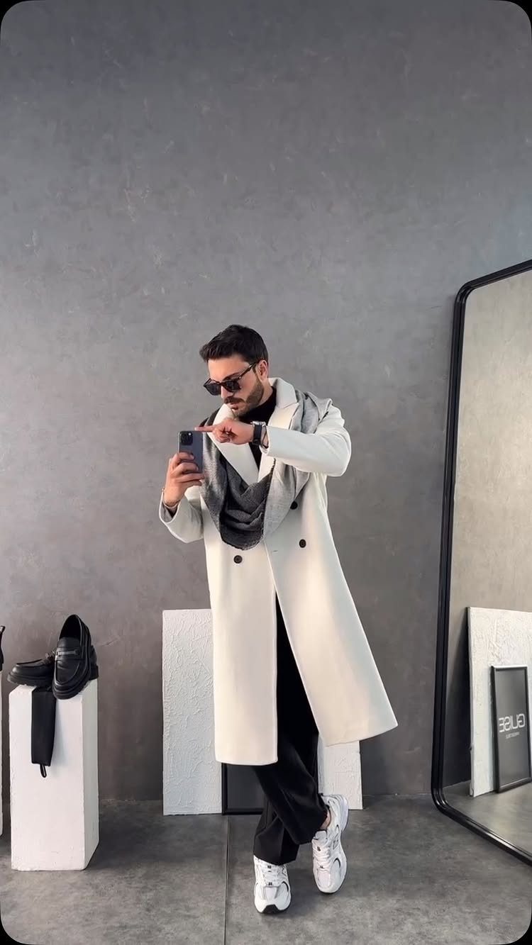 Man in white trench coat, grey scarf, black trousers, and white sneakers.