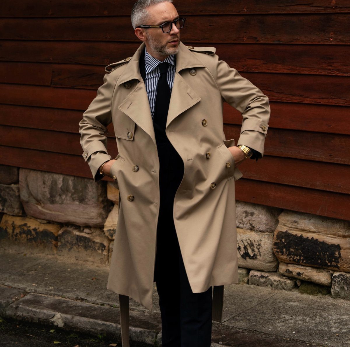 Man in a beige trench coat worn over a dark suit and tie.