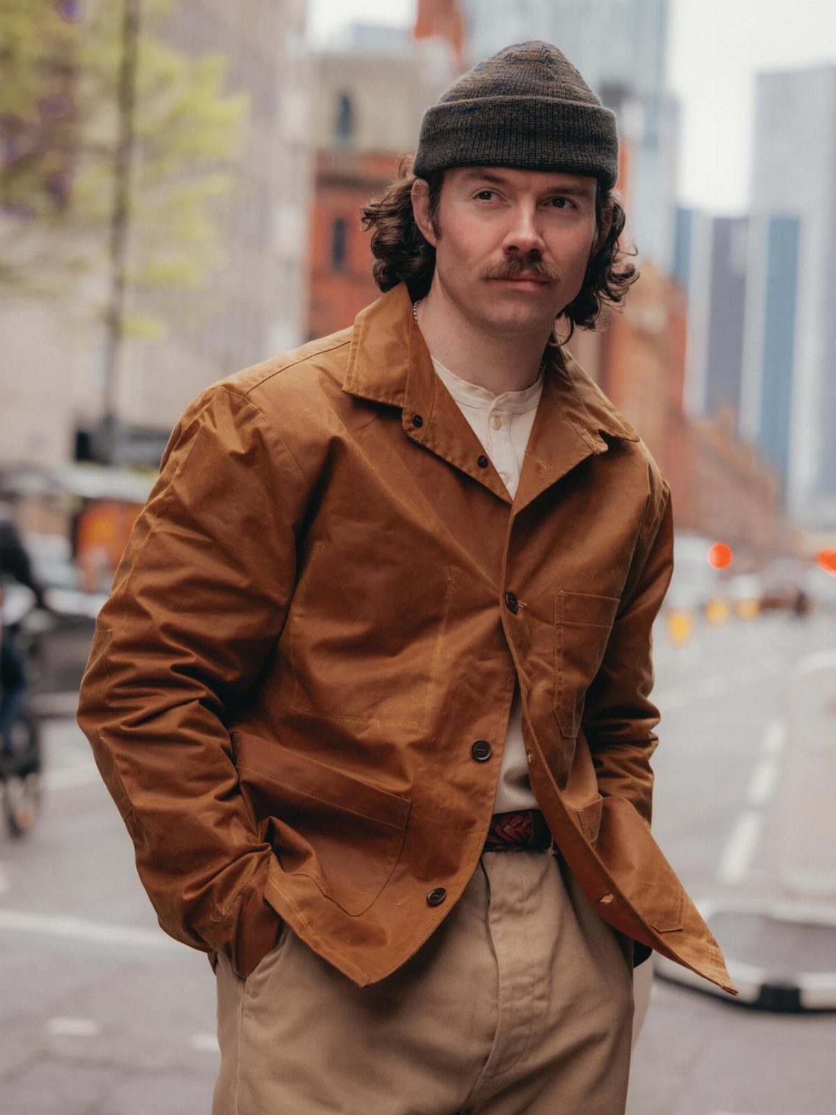 Man wearing a brown canvas chore coat and grey beanie on a city street