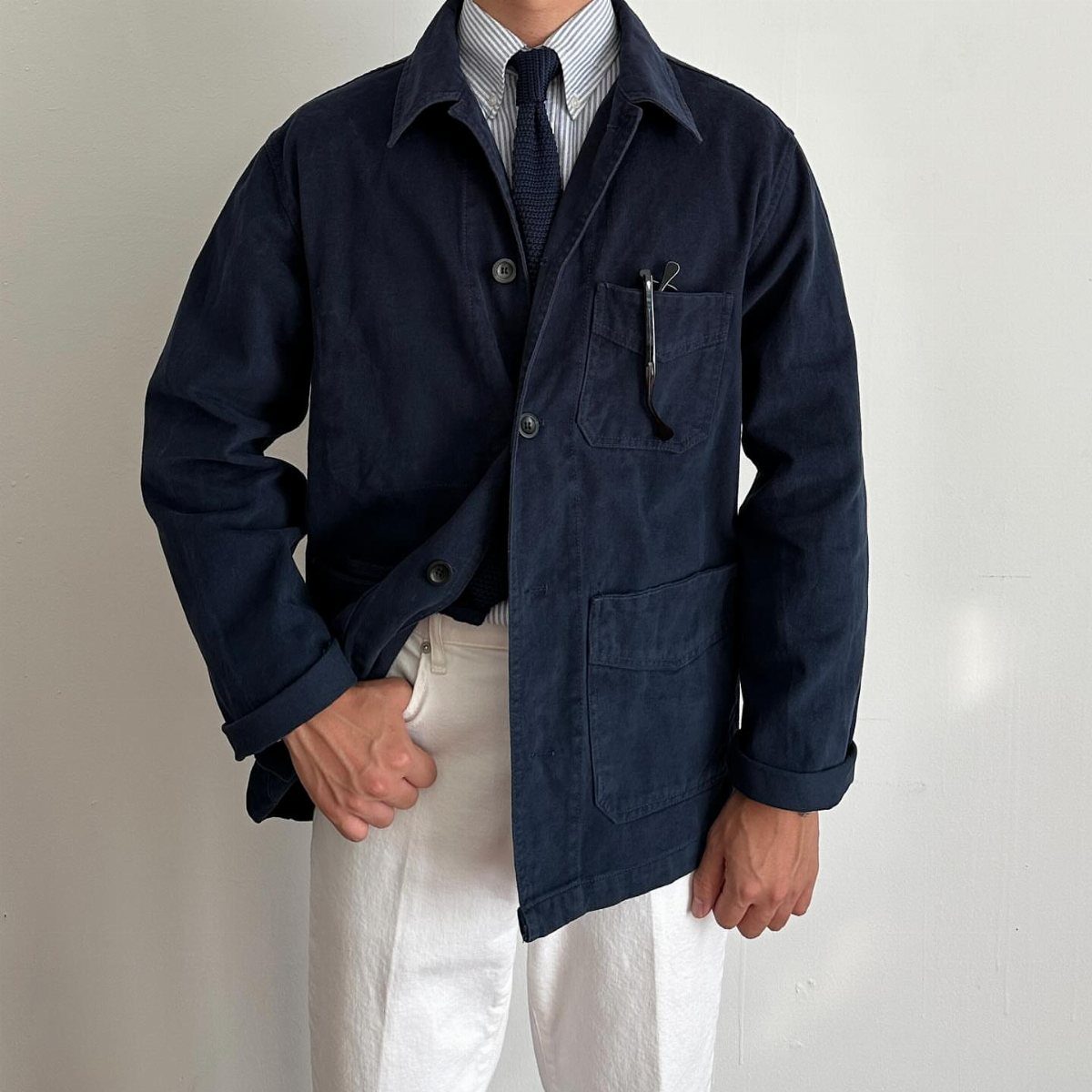 Navy blue chore coat with patch pockets worn over a striped shirt and tie.