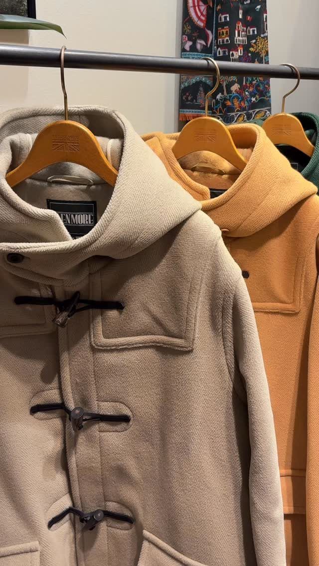 Beige and mustard yellow wool duffle coats with toggle buttons on hangers.