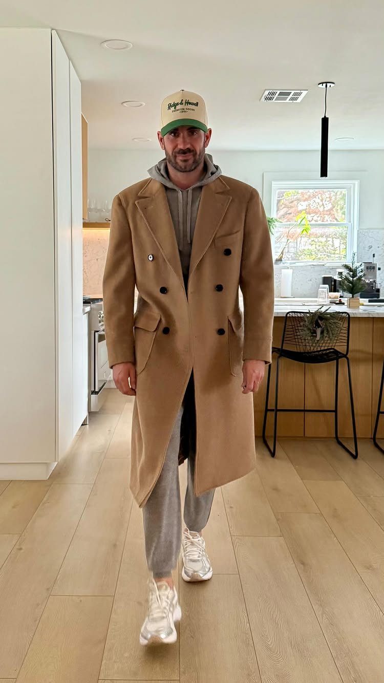 Man wearing a camel wool overcoat with a grey hoodie and joggers.