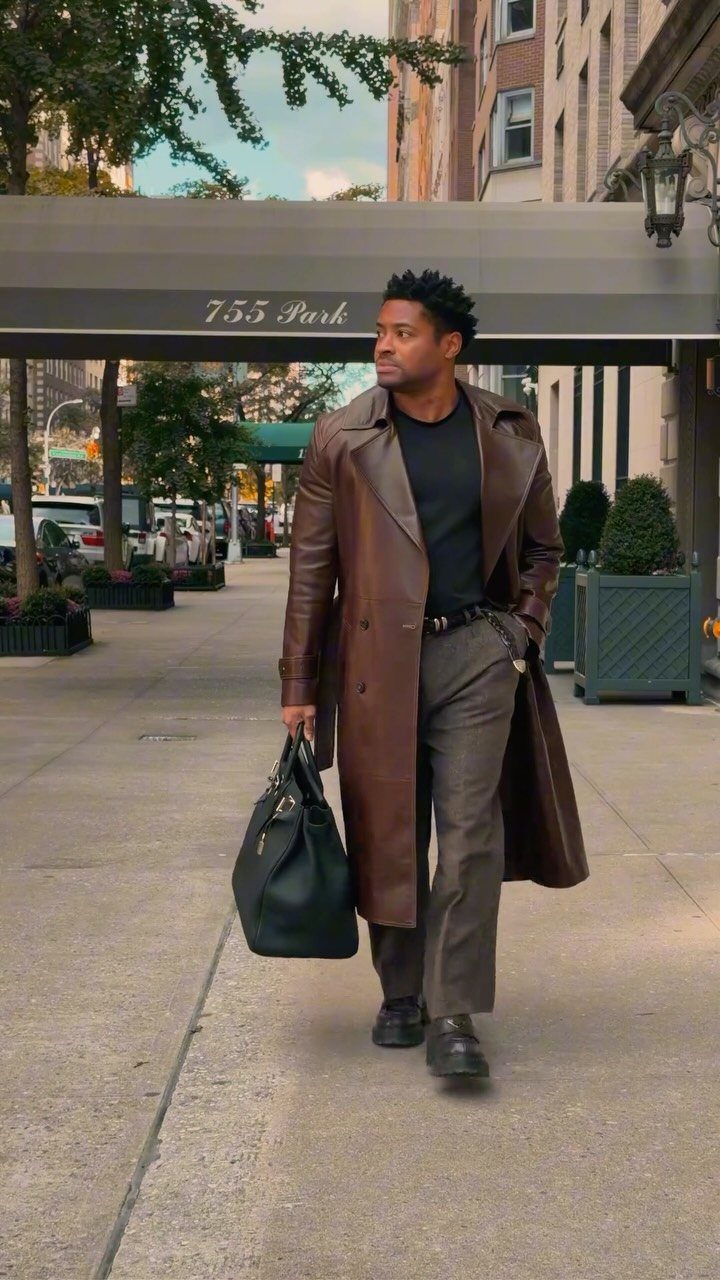 Man in a brown leather trench coat walking on a New York City sidewalk